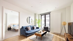 A modern living room with a blue sofa, a wooden coffee table, and a large mirror. - Croydon by Charles Hope (Croydon)
