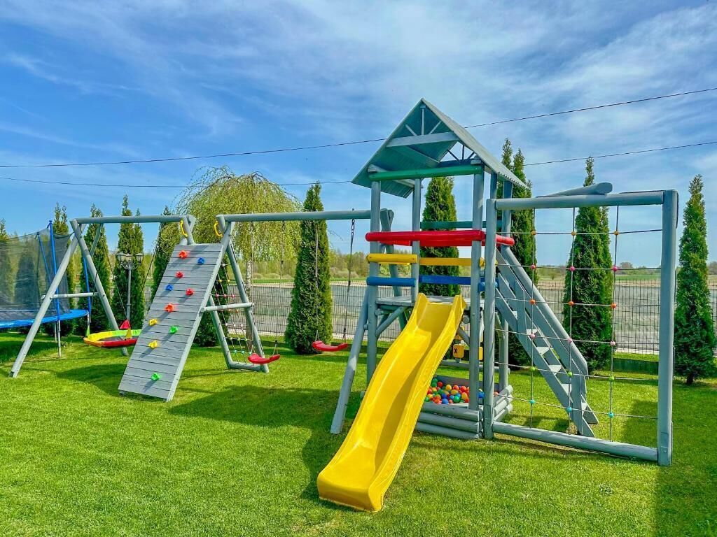 Un parque infantil con tobogán, pared de escalar y columpios.