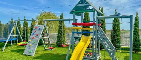 Un parque infantil con tobogán, pared de escalar y columpios.