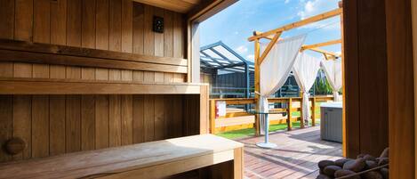 A sauna room with wooden benches and a view of an outdoor deck.