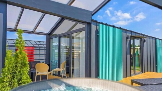 Un área exterior moderna con jacuzzi, puertas de vidrio, un espacio para sentarse y vistas al cielo.