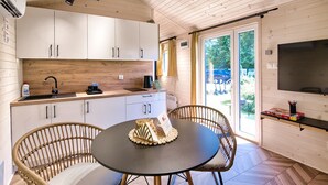 Una cocina moderna con armarios blancos, una encimera negra y un comedor con sillas de mimbre.