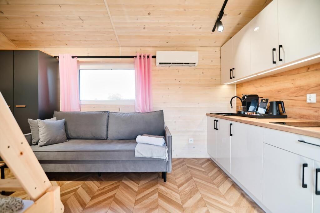 A compact living space with a sofa, kitchenette, and wooden flooring.