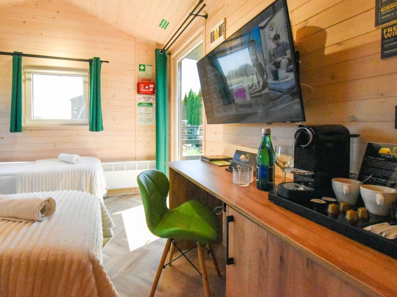 A hotel room with two beds, a television, a coffee machine, and a small bar area.