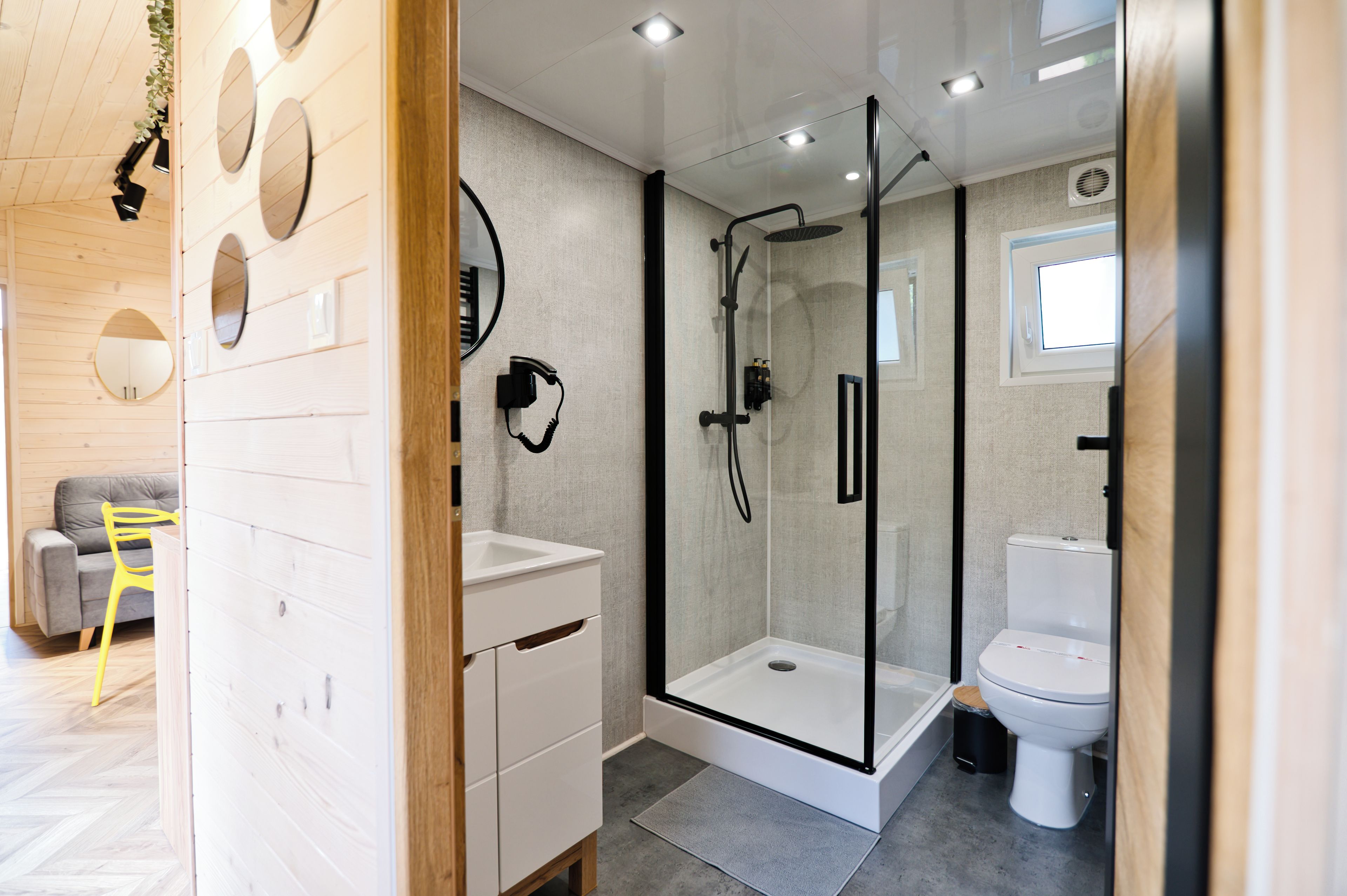 A modern bathroom with a glass-enclosed shower, a white sink, and a toilet.