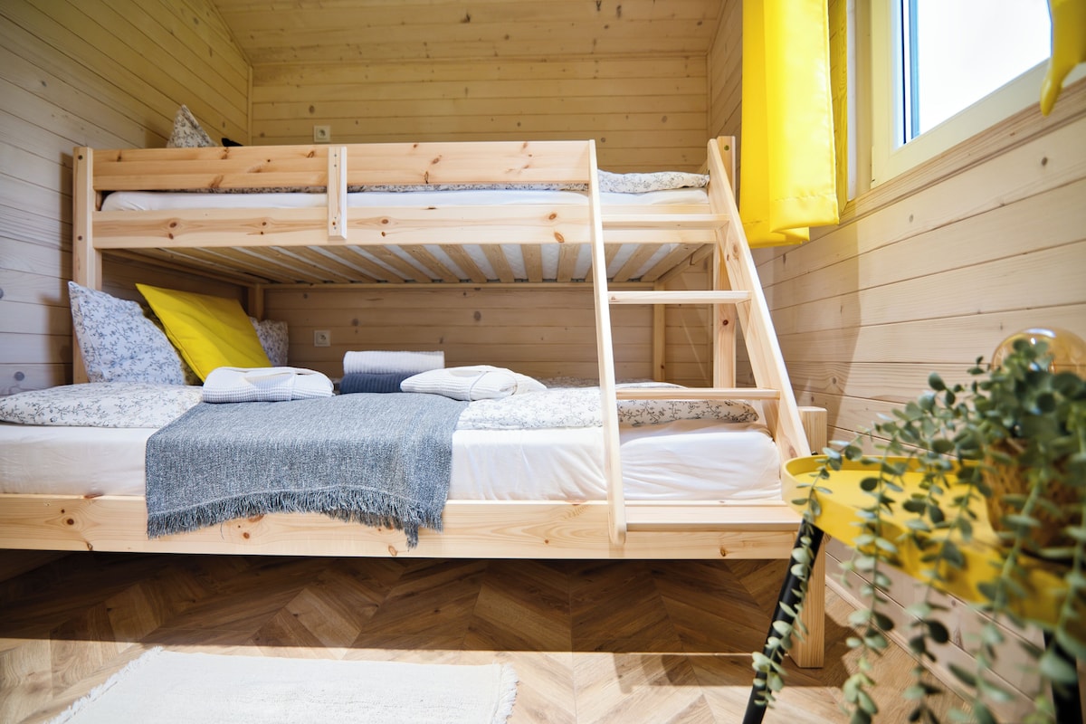Ein Stockbett mit Holzleiter, einer weißen Matratze und einer blauen Decke.