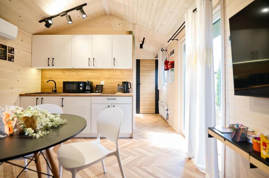 A modern kitchen with white cabinets, a black countertop, and a dining area with a table and chairs.