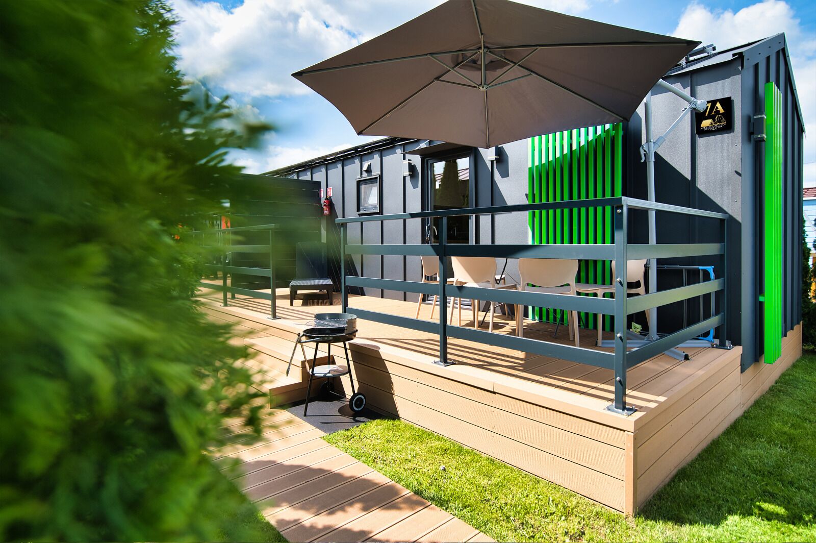 A modern outdoor seating area with a grill, chairs, and a large umbrella.