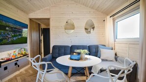 A cozy room with a wooden ceiling, a large window, a blue sofa, a white table, and two white chairs. - Holiday Park Zator Resort & Spa (gmina Przeciszów)