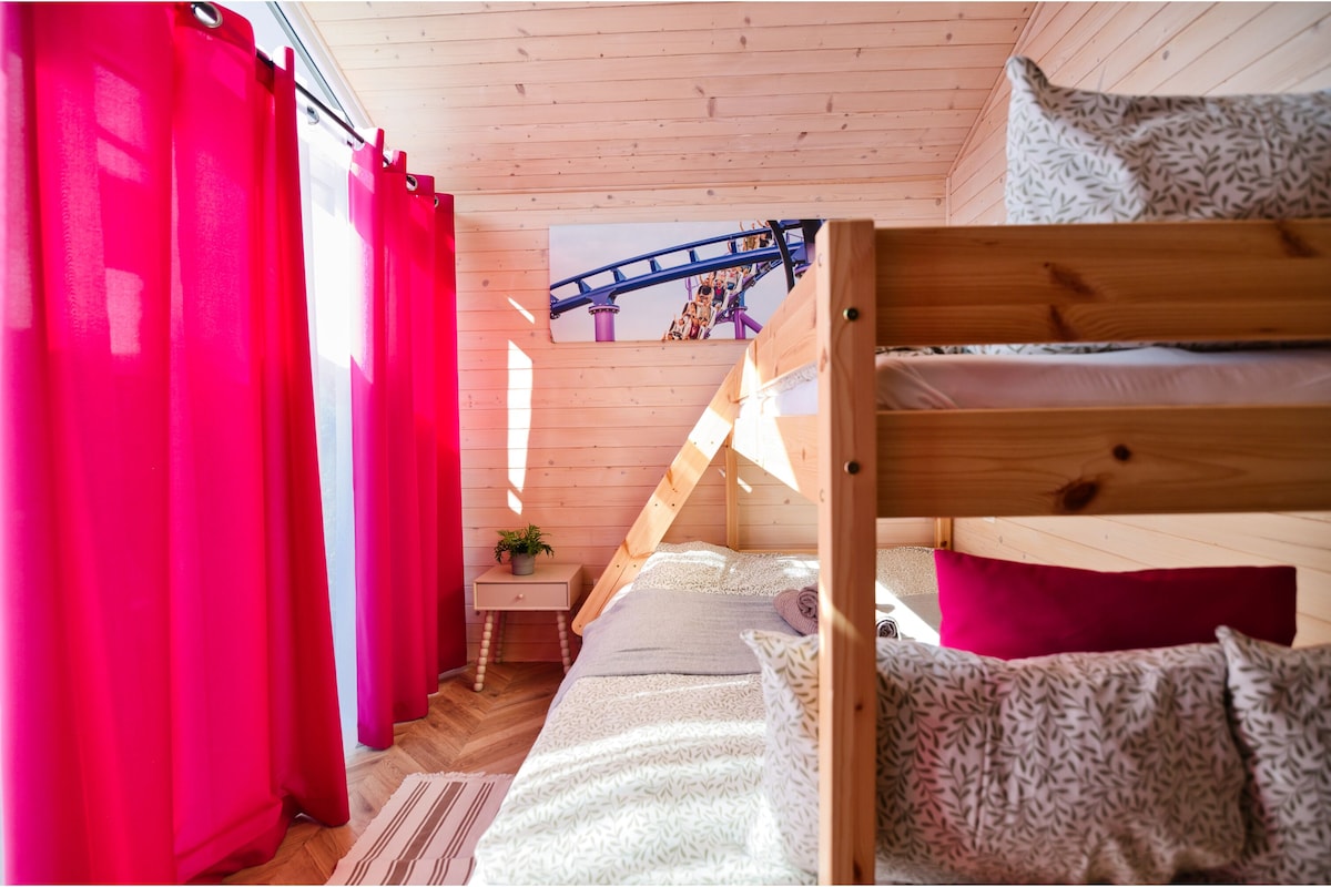 Ein gemütliches Schlafzimmer mit einem Etagenbett, einem kleinen Nachttisch mit Pflanze und einem Poster von Achterbahn.