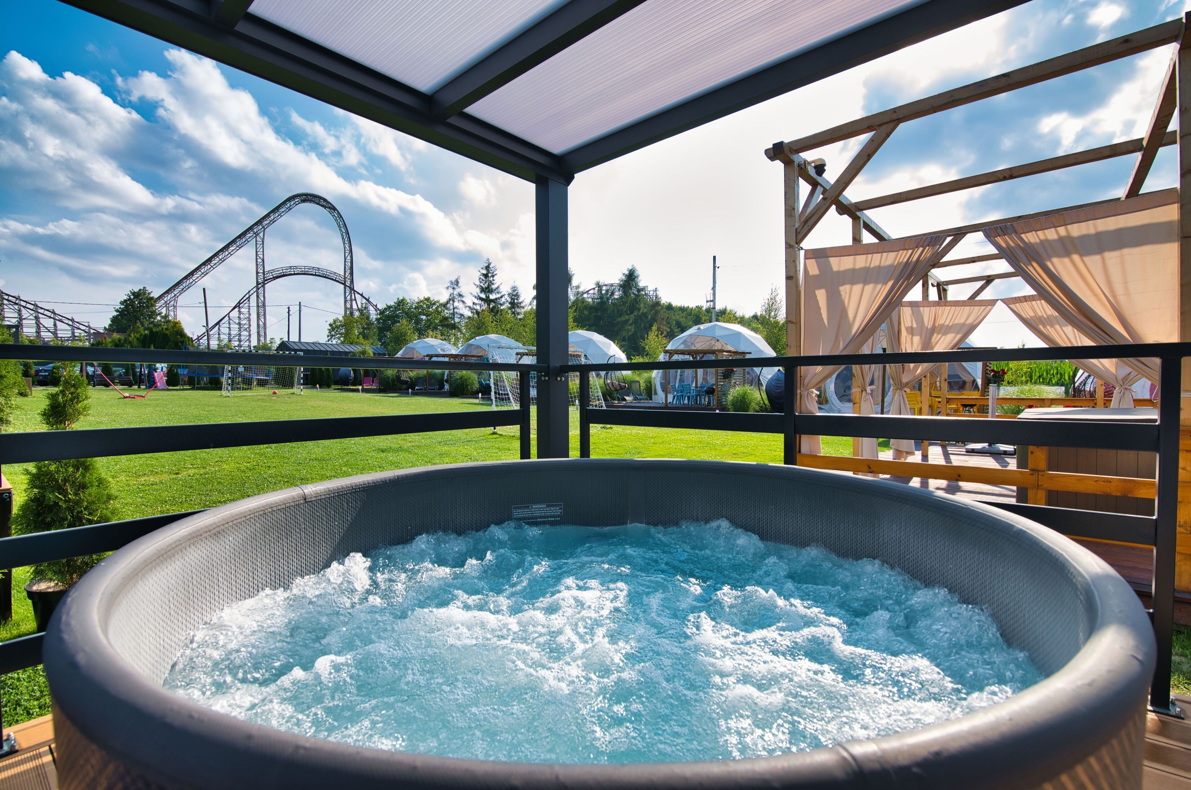 Un jacuzzi con vistas a una montaña rusa y campos verdes.