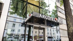 The exterior of the ARCOTEL AQ building with large glass windows reflecting the surrounding area. - ARCOTEL AQ Wien (Vienna)