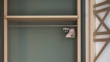 Una habitación moderna con un armario empotrado de madera, una mesita de noche y una cama con un cojín verde.