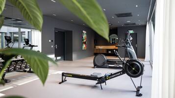 Un gimnasio moderno con máquinas de remo, mancuernas y un espejo grande.