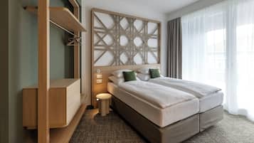 Et moderne hotelværelse med en stor seng, et træhovedgærde, et lille natbord og en indbygget bænk.