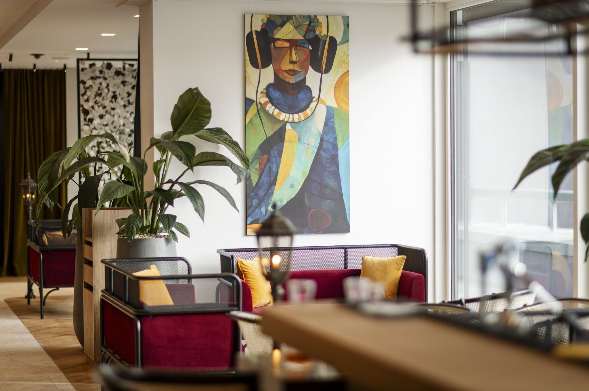 A modern lobby with seating areas, a large abstract painting, and potted plants.
