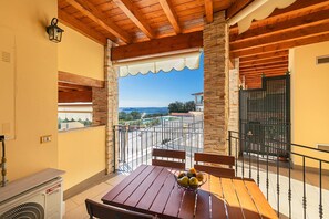 A balcony with a wooden table, chairs, and a bowl of fruit. - Le Terrazze PT 36 by Wonderful Italy (Toscolano Maderno)