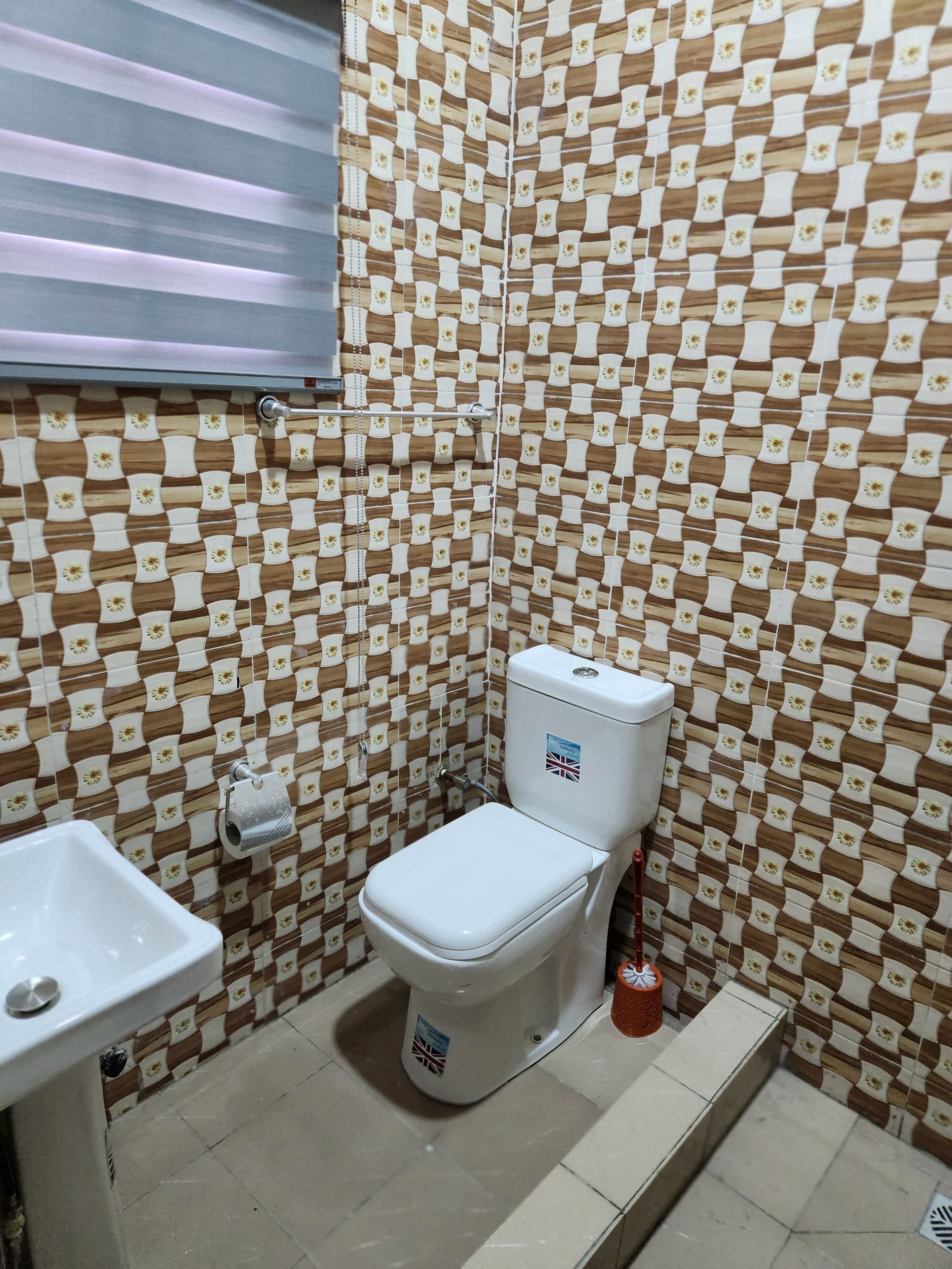 Un baño con inodoro, lavamanos y azulejos estampados.