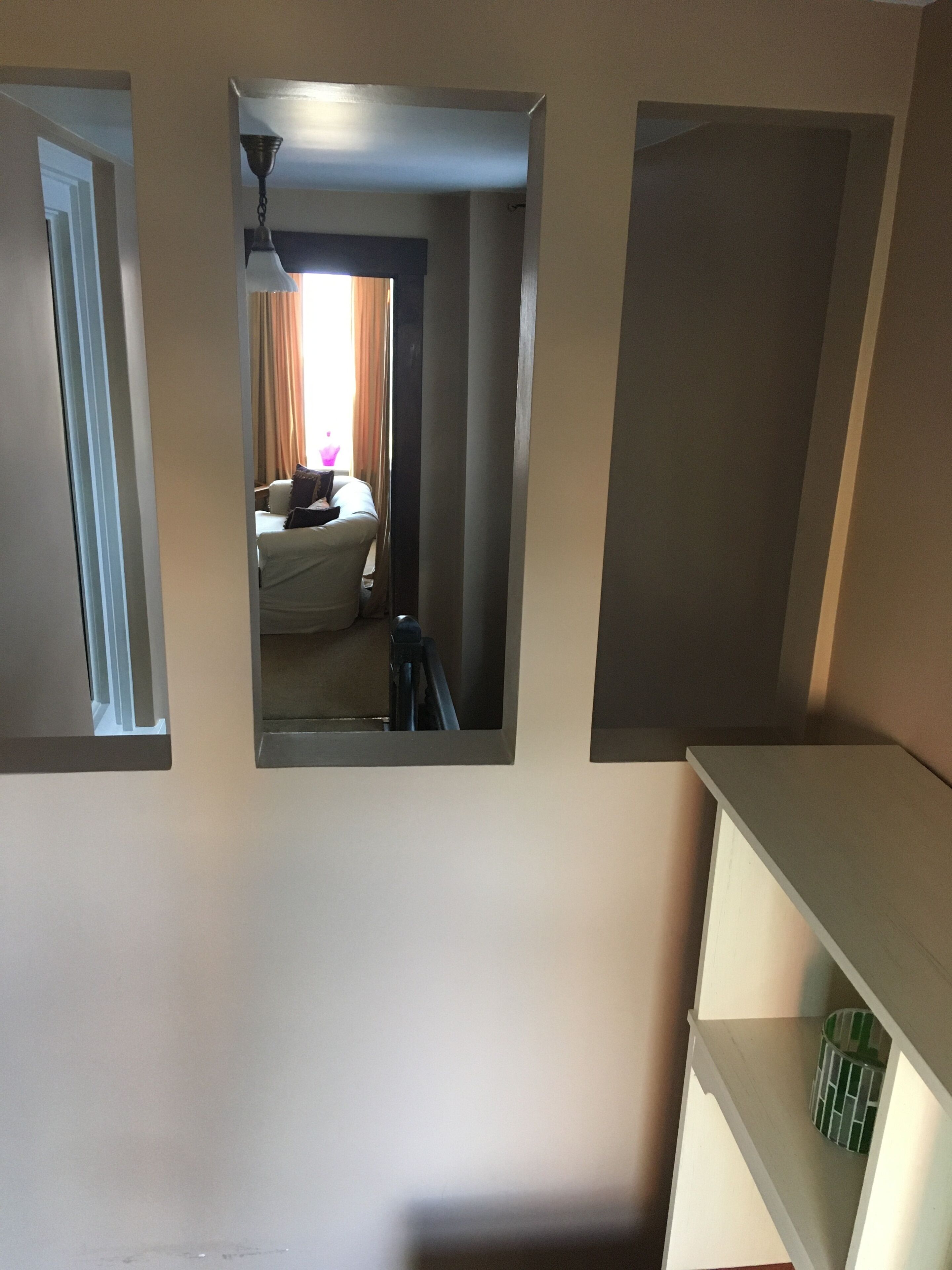 A room with a bed, a desk, and a chair. There is a window with curtains and a view of the outside.
