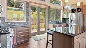 A modern kitchen with large windows, a central island, and stainless steel appliances.