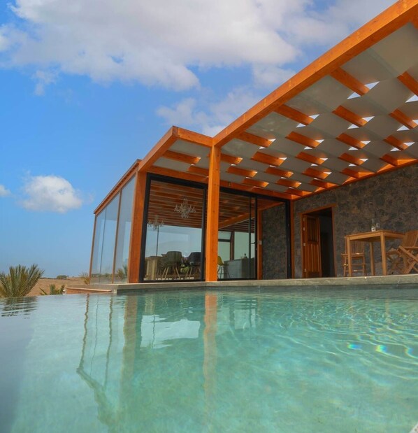 Una casa moderna con un porche de vidrio y una piscina.