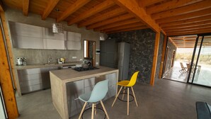 A modern kitchen with a central island, two bar stools, and a view of the outdoors. - Casa Julie, Ferien in Absoluter Ruhe (La Pared)