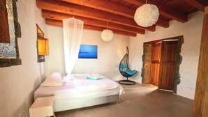 A bedroom with a bed, a hanging chair, and a wooden door. - Casa Julie, Ferien in Absoluter Ruhe (La Pared)