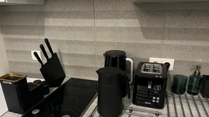 Una cucina con piano cottura a induzione nero, una macchina da caffè, un tostapane e un bollitore.