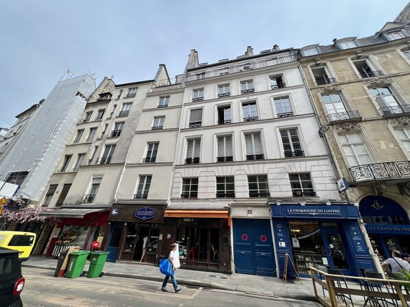 A multi-story building with a storefront labeled "Les Caves du Louvre" and a blue door with a no parking sign. - Louvre-Rivoli 1 bedroom apartment (Paris)