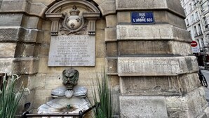 Un monumento in pietra con iscrizioni, una targa e una fontana.