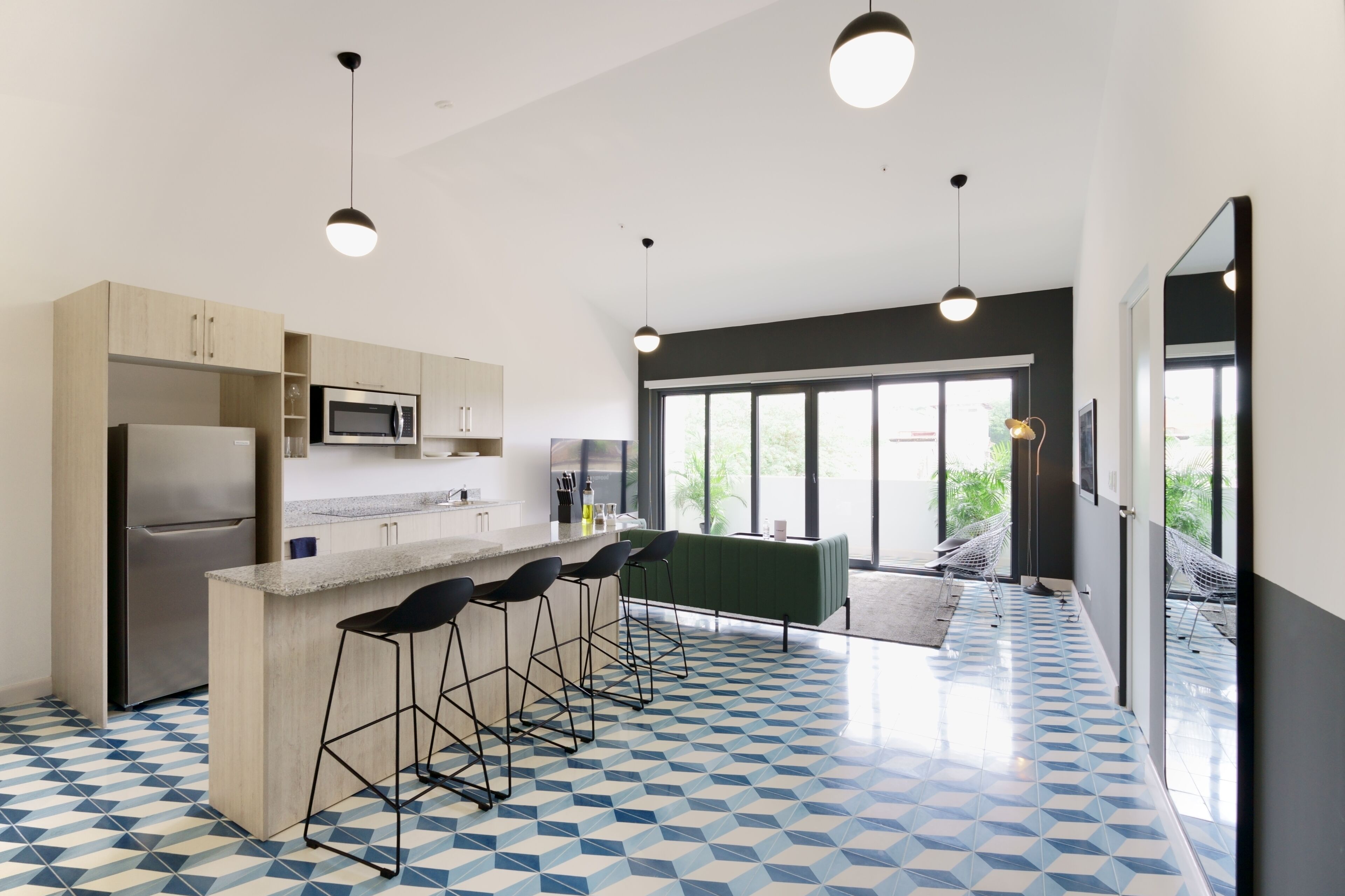 A modern kitchen with a central island, bar stools, a microwave, and a refrigerator.