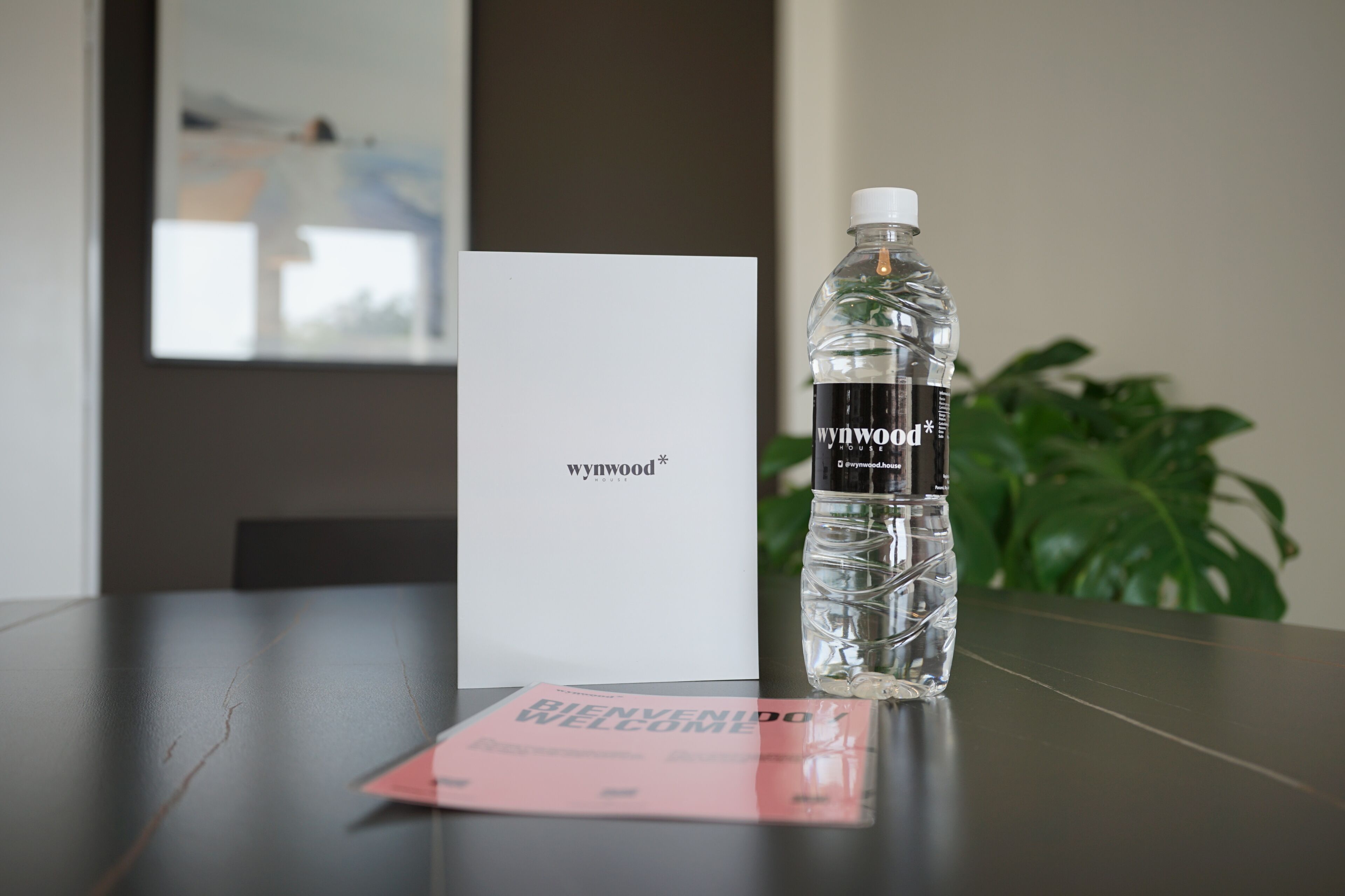 Une bouteille d’eau de Wynwood, une carte de bienvenue et une carte blanche sur une table.