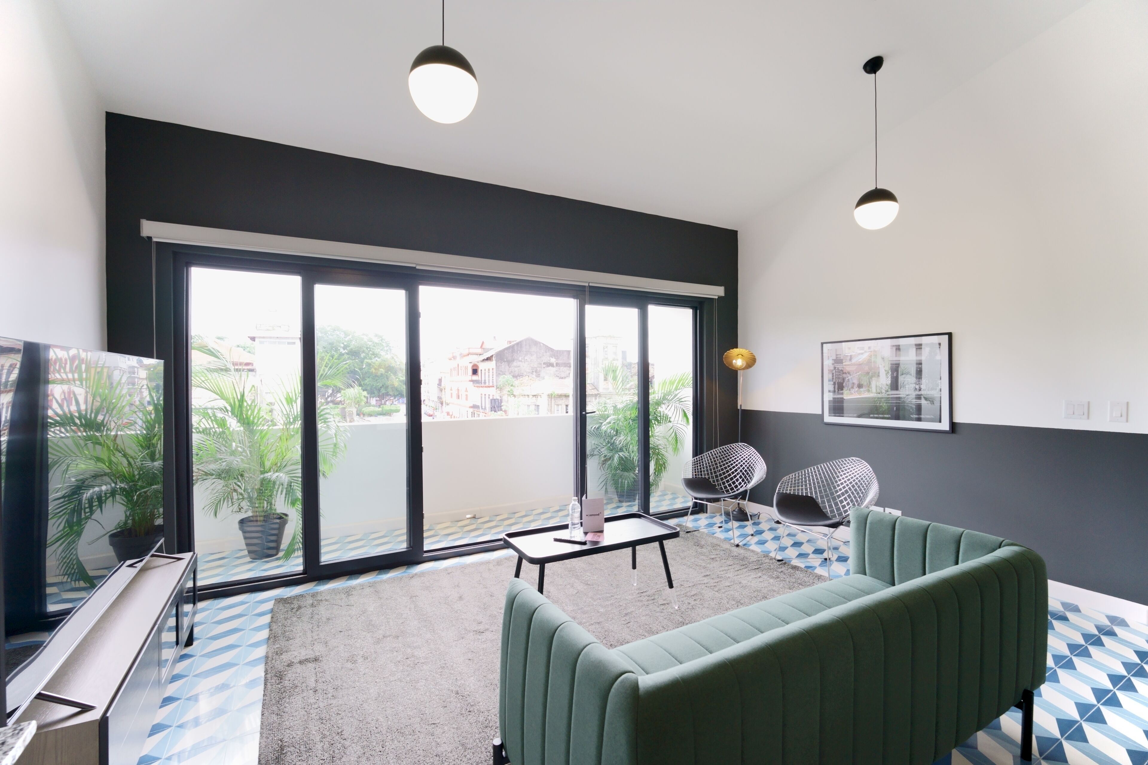 A modern living room with a green sofa, a small table, and a TV.