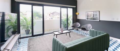 A modern living room with a green sofa, a small table, and a TV.