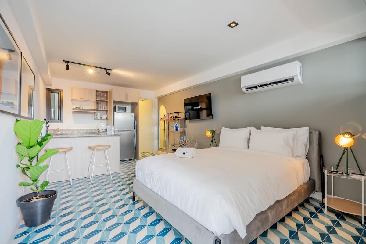 Ein modernes Hotelzimmer mit einem großen Bett, einer kleinen Küchenzeile und einer Essecke.