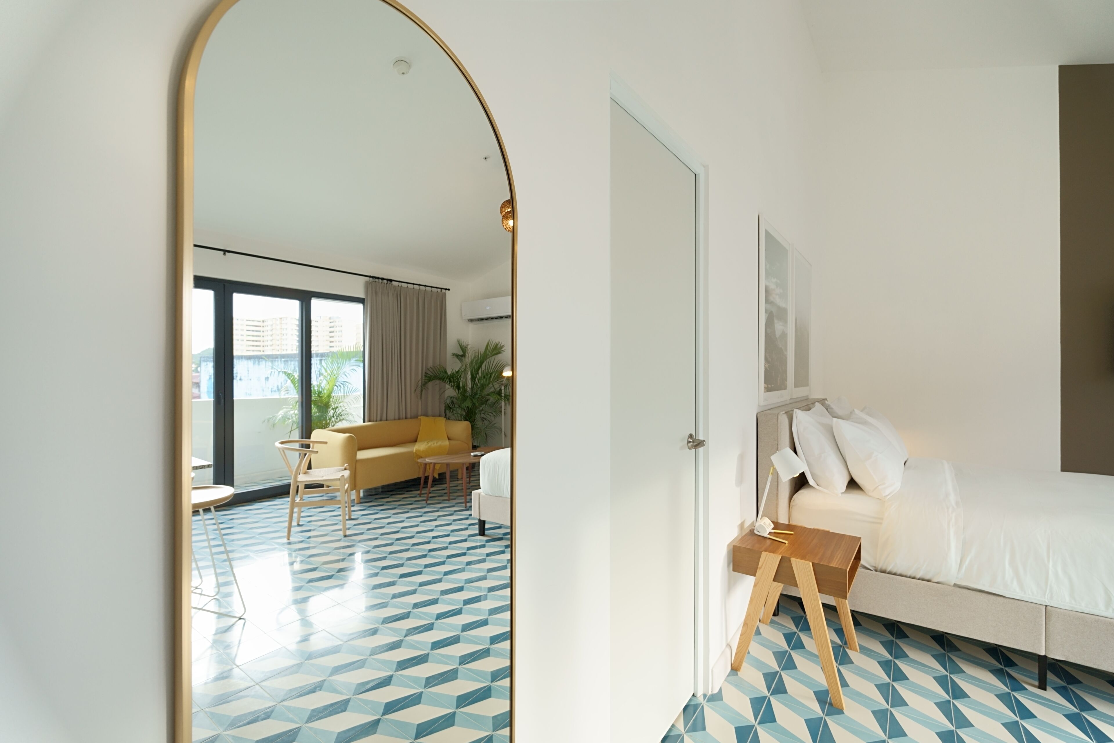 Una habitación de hotel con un espejo grande, una cama, un sofá y una mesita.