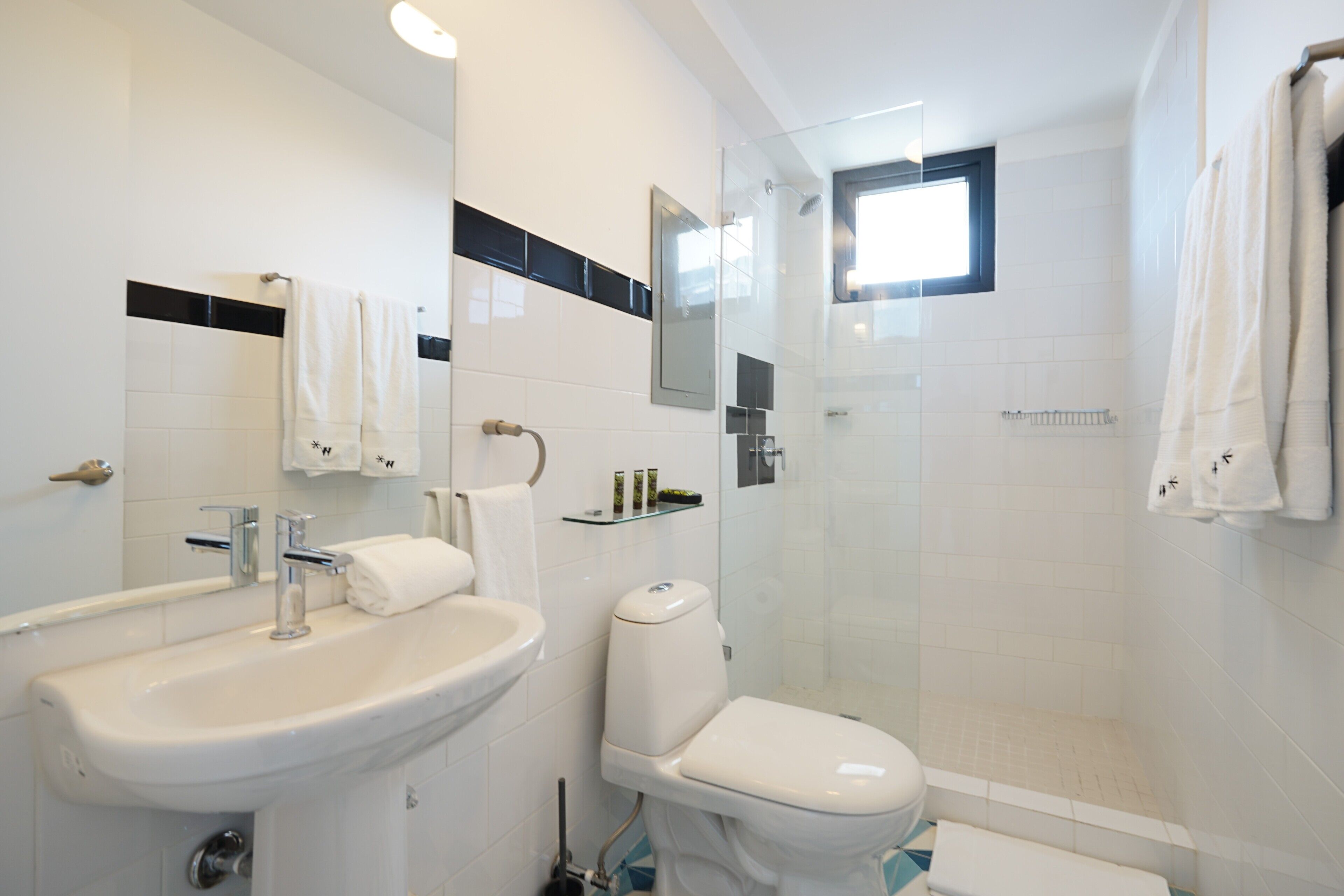 Un baño moderno con lavamanos, inodoro y ducha con mampara de vidrio.
