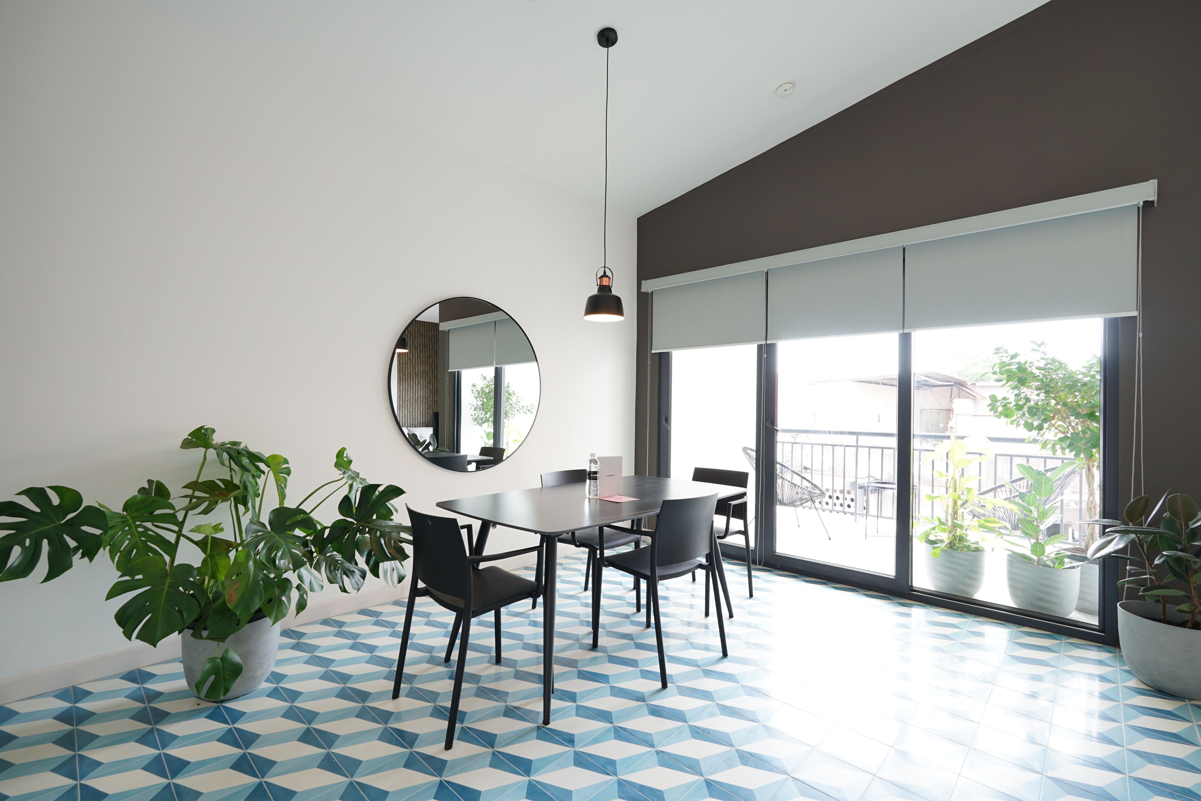 Un espace repas moderne avec une table ronde, des chaises, une plante en pot et une grande fenêtre.