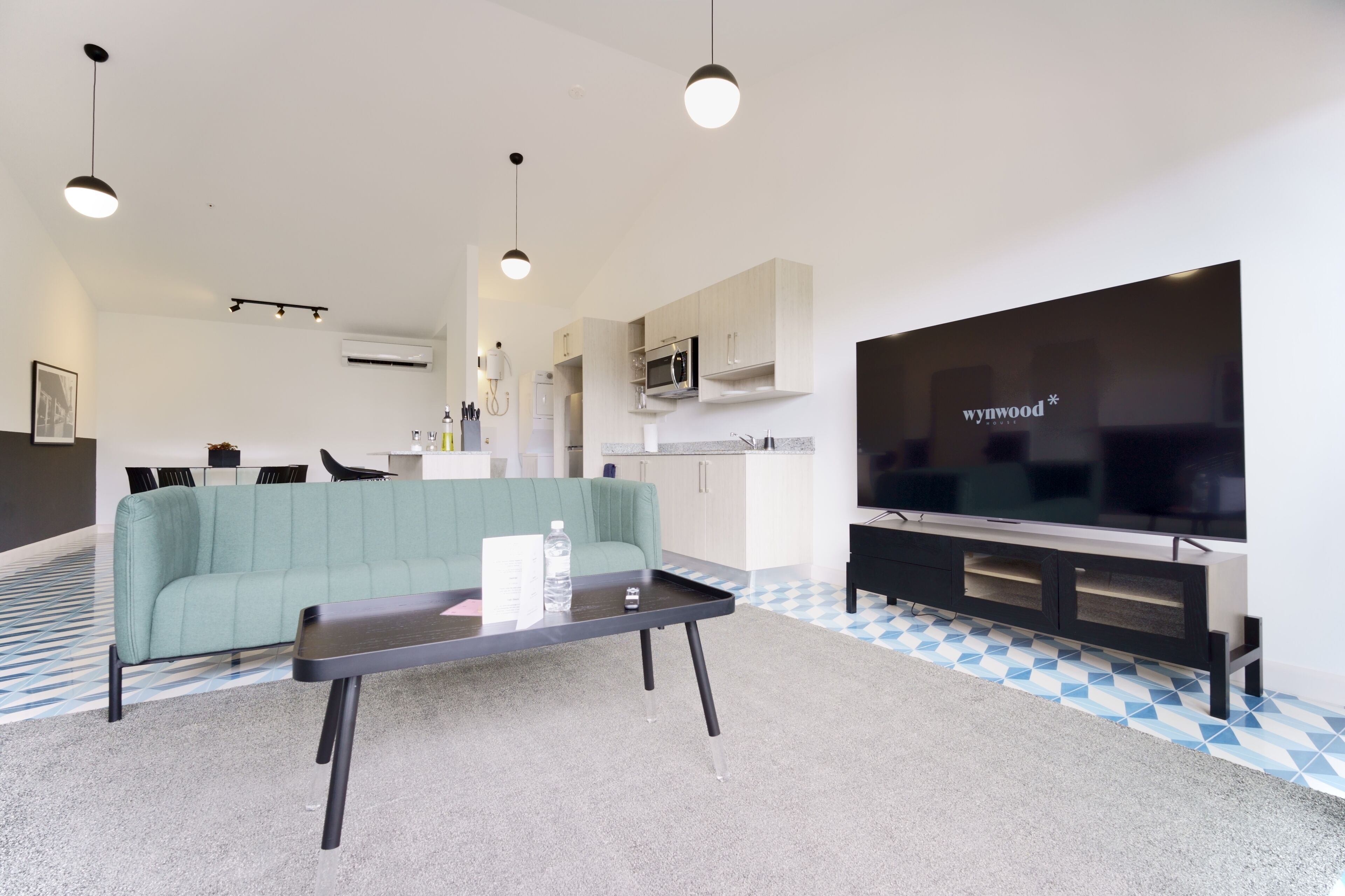 Una sala de estar moderna con un televisor de pantalla plana, un sofá verde y una mesa de centro.