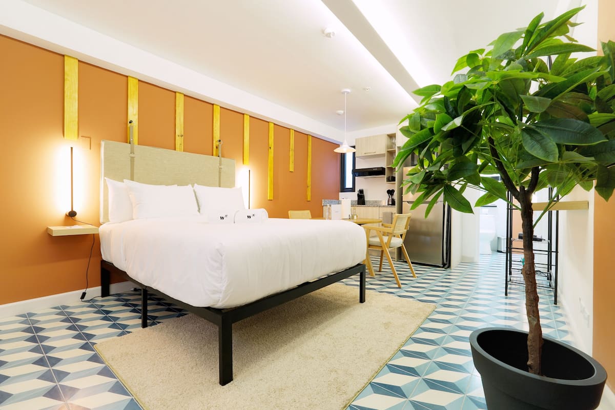 Ein modernes Hotelzimmer mit Bett, Nachttisch und einer Topfpflanze.