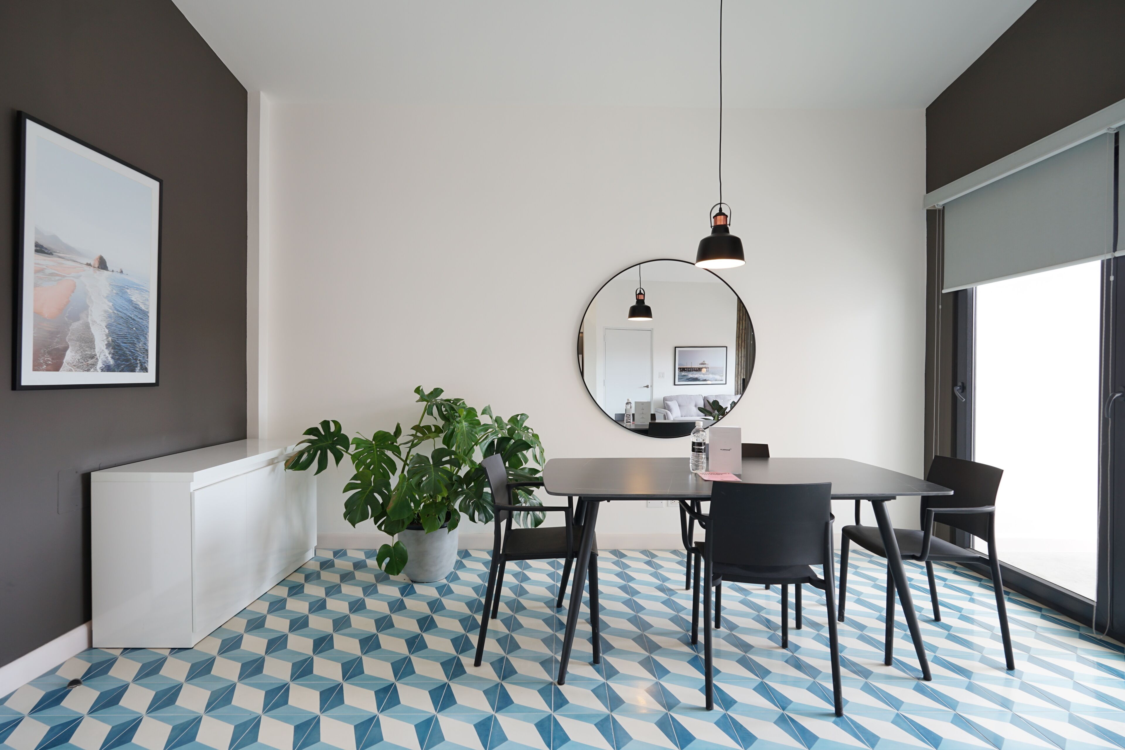 A modern room with a checkered floor, a white desk, a large mirror, and a potted plant.