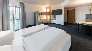 Una habitación de hotel con dos camas, un escritorio, un televisor y una ventana con cortinas.