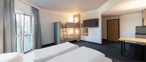 Une chambre d’hôtel avec deux lits, un bureau, une télévision et une fenêtre avec des rideaux.