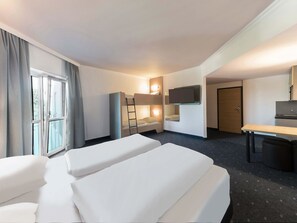 Una habitación de hotel con dos camas, un escritorio, un televisor y una ventana con cortinas.
