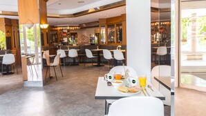 Un restaurante moderno con zona de bar, diferentes disposiciones de asientos y preparación para el desayuno.