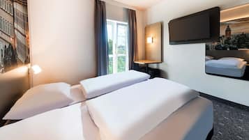 Een hotelkamer met twee bedden, een aan de muur bevestigde televisie, een raam met gordijnen en een lamp.