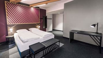 Una habitación de hotel moderna con una cama, mesitas de noche, un escritorio y un banco.