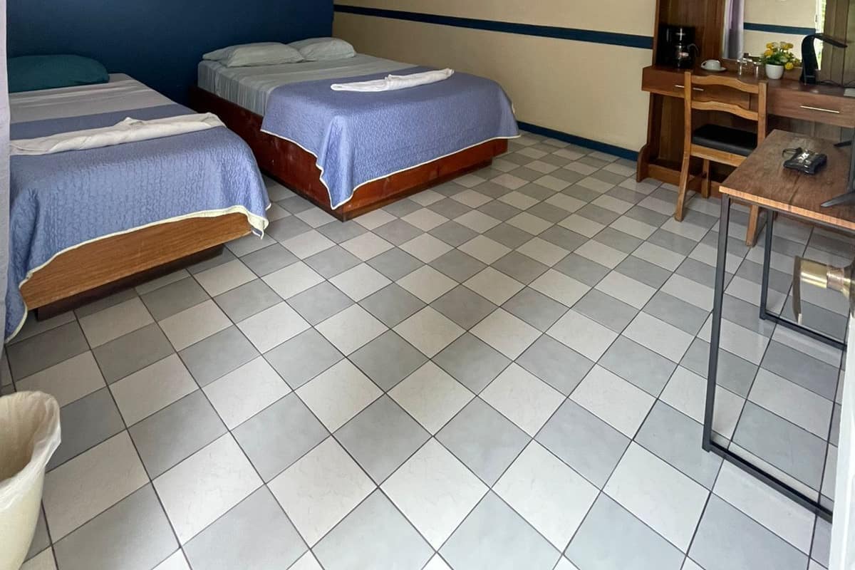 A room with two beds, a desk, a chair, and a small table.