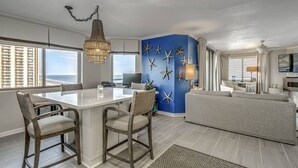 A modern living room with a large window, a dining area with a chandelier, and a blue accent wall with starfish decorations. - Blue Ocean Front Escape (MYRTLE BEACH)