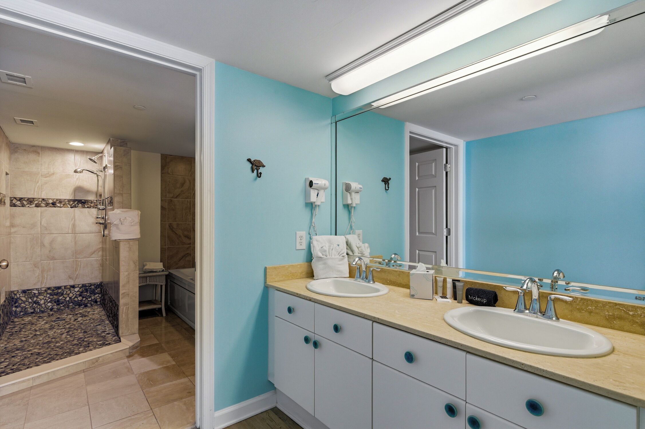 Une salle de bain avec deux lavabos, un grand miroir et un espace douche.